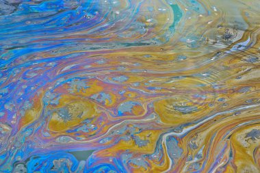 Surface water of a Texas bayou with ripples, showing a colorful oily film on top, signifying polluted oily waters. clipart