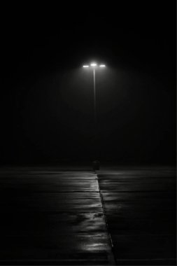 Sisli sabahı güneş doğmadan önce bir sokak lambası. Hafif sis yavaşça yere ilginç gölgeler ve dokular ile bir Film noir hissediyorum veren ışık, yükselir..