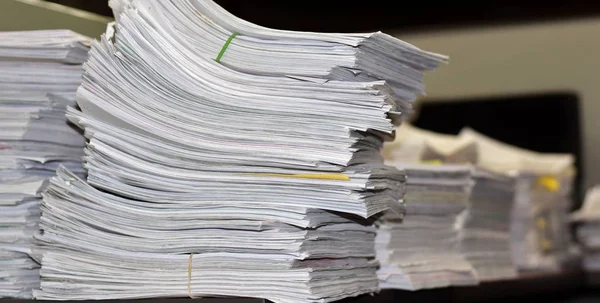 Office papers stacked up along a desk in an organized fashion.