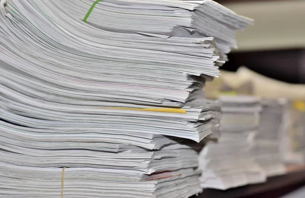 Stacks and stacks of paperwork sitting on an office desk in a messy but organized fashion. Suggests a stressful environment where deadlines must be met.