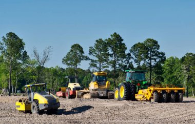 Land being cleared for development with heavy machinery bulldozers and scrapers parked in the background. clipart