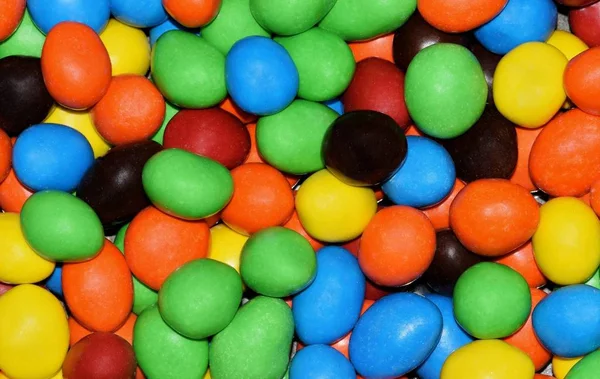 An assortment of colors in the form of round hard candies seen close up with a macro lens and filling the frame.