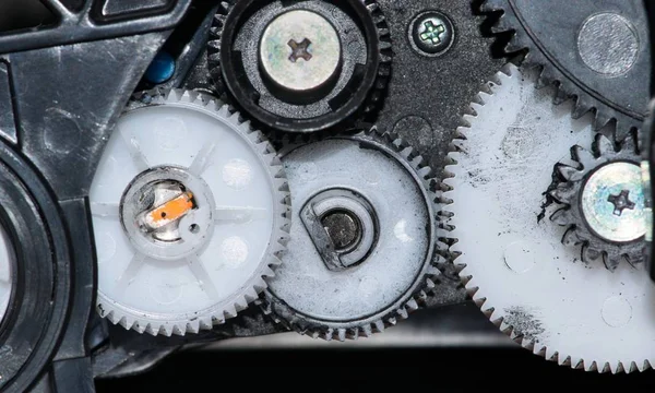 Close up view of ink-stained plastic cog wheels and screws and other components from a printer cartridge.