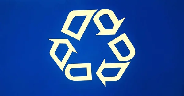 Blue recycle logo on an aluminum receptacle, promoting the use of recycled materials to help save the environment.