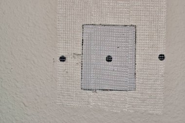 Duvardaki alçıpan onarımları, kare tamir panelini kaplayan fiberglas bant destek için vidalanmış. Uzayı resmin sol tarafına kopyala. Onarım, DIY ev bakımı, adım adım.