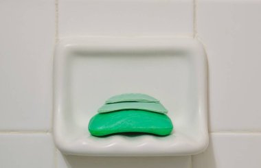 Banyo duş tutacağı ve beyaz fayans arka planında duran eski sabun kalıpları. Atık konseptinin geri dönüşümü.