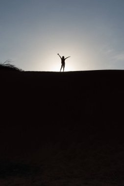 Kumul bir akşam mavi gökyüzü arka plan karşı bir kız güzel bir siluet. 