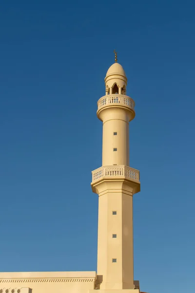 Una guglia e un minareto di una moschea bianca e arancione con un cielo blu — Foto Stock