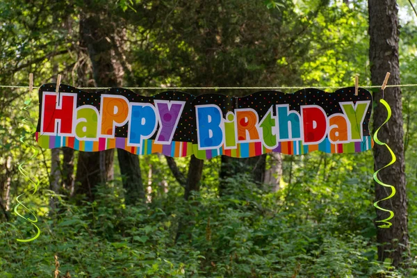Happy Birthday sign panorama in the outdoor trees with balloons