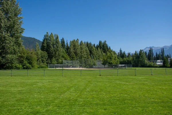 Пустой бейсбол или софтбольный бриллиант с задней ограды и грязной линии глядя на траву и деревья в Уистлер, Британская Колумбия, Канада . — стоковое фото