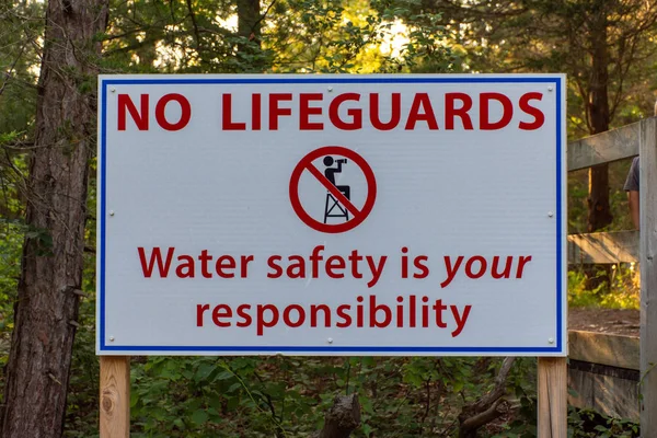 Water Safety sign stating no lifeguards on duty and to take care while swimming in the lake.