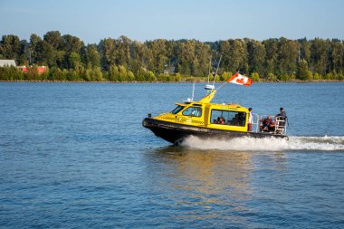 New Westminster Rıhtımı'nda, sarı bir taksi feribot sürat teknesi Kanada bayrağı ile Queensbourgh rıhtım iskelesinden seyahat