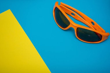 Parlak mavi ve sarı düz arka plan dizaynlı, fotokopi alanı olan turuncu güneş gözlükleri. Yaz eğlencesine hazırım..