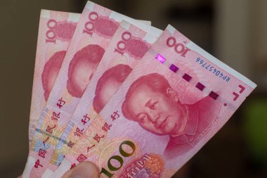 Çin 'in para birimine el verenler - kahverengi arkaplana yayılmış yüz adet kırmızı renminbi veya yuan banknotları. Para değişimi.