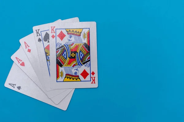 Full house hand of cards on bright blue flat lay in a game of texas holdem poker gambling at a casino concept.