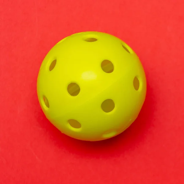 Φωτεινό Κίτρινο Pickleball Whiffle Μπάλα Ένα Στερεό Φωτεινό Κόκκινο Επίπεδο — Φωτογραφία Αρχείου