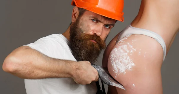 Bearded man worker, beard. Female ass in underwear. Plastering tools. Naked body. Big ass, gorgeous bum, sexy girl. Tool, trowel, handyman, man builder. Ass, bum, butt. Builders in hard hat, helmet