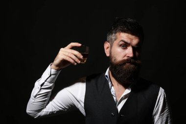 Elinde cam viski tutan zengin bir adam. Viskili çekici bir adam. Takım elbiseli şık yakışıklı erkek cam brendi ve konyaktan içer. Zarif smokinli yakışıklı bir sakalın portresi, konyak iç.