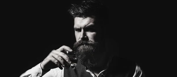 Bearded male. Stylish handsome male in suit drink from glass brandy, cognac. Portrait of a handsome bearded in elegant tuxedo, drink cognac. Attractive man with a whiskey. Black and white