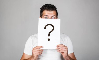 Soru işareti, sembol. Düşünceli erkek. Adam bir soru. Şüpheli adam soru işareti tutarak. Sorunlar ve çözümleri. Yanıt almaya. Adam, arkasında sorgulama sembolü bakmak portresi. Erkek izole