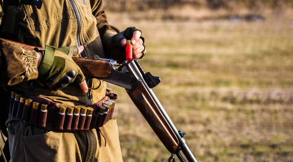 The man is on the hunt, sport. Hunter man. Hunting period. Male with a gun, rifle. Man is charging a hunting rifle. Process of hunting during hunting season. Male hunter in ready to hunt. Closeup