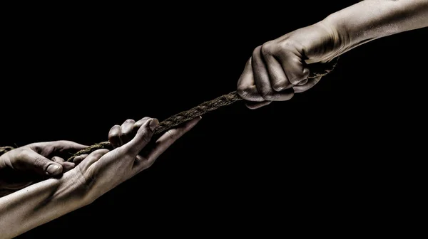 Hand holding a rope, climbing rope, strength and determination. Rescue, help, helping gesture or hands. Conflict, tug of war. Two hands, helping hand, arm, friendship. Teamwork, friendship. Rope, cor