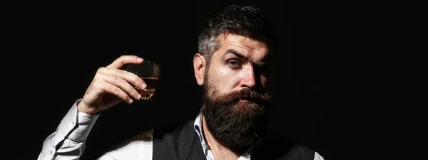 Un om de afaceri cu barbă ţine un pahar de whisky. Frumos om bine îmbrăcat în jachetă cu pahar de băutură. Adult om de afaceri elegant de succes purtând costum și băut whisky, coniac, coniac — Fotografie, imagine de stoc