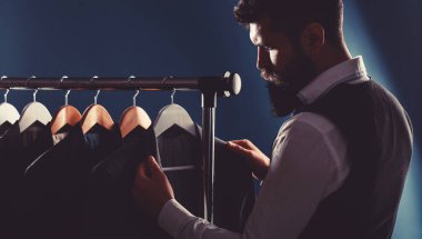 Terzi, terzilik. Erkek kıyafeti, atölyesinde terzi. Zarif adamlar peş peşe asılıyor. Lüks erkekler şık erkek mağazasında raflarda klasik takım elbiseler.