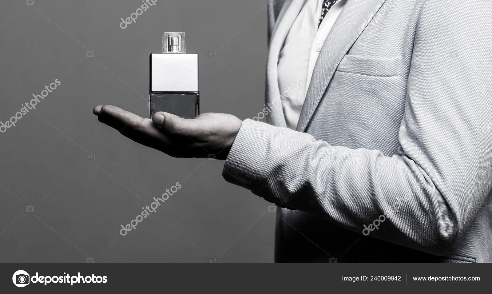 Masculine perfume, man in a suit. Man perfume, fragrance. Male holding up  bottle of perfume. Perfume