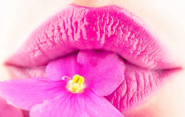 Labbra ravvicinate e fiore. Primo piano bel labbro femminile con trucco di lucentezza di rossetto lucente. Spa e cosmetici. Labbra con fiori, bocca sexy, natura — Foto Stock