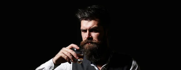 Retrato de un guapo barbudo en elegante esmoquin, beber coñac. Un hombre atractivo con un whisky. Varón barbudo. Elegante macho guapo en traje bebida de brandy de vidrio, coñac —  Fotos de Stock