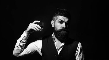 Elinde cam viski tutan zengin bir adam. Viskili çekici bir adam. Takım elbiseli şık yakışıklı erkek cam brendi ve konyaktan içer. Zarif smokinli yakışıklı bir sakalın portresi, konyak iç.