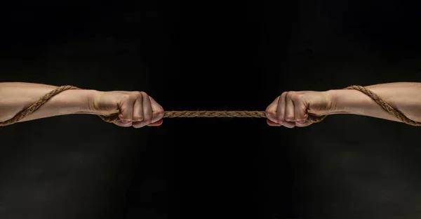 Conflict, tug-of-war, rope. Hand holding a rope, climbing rope, strength and determination concept. Safety. Macro shot isolated over black background.