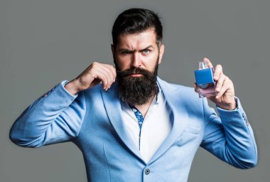 Sakallı adam parfüm şişesi tutuyor. Moda kolonya şişesi. Sakallı erkek pahalı koku kokusu tercih eder. İnsan parfümü, koku. Erkeksi parfüm. Erkek koku ve parfümeri, kozmetik