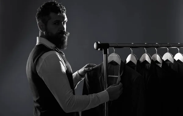 Abbigliamento uomo, shopping in boutique. Sartoria, sartoria. Vestito da uomo, sarto nel suo laboratorio. Eleganti abiti da uomo appesi di fila. Uomo di lusso abiti classici su rack in eleganti mens boutiqu — Foto Stock