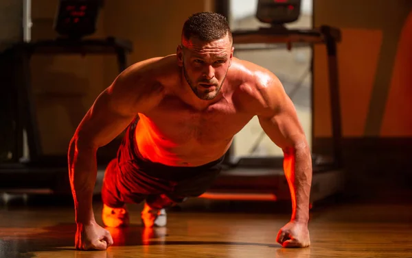 Człowiek robi pompki. Muskularny i silny facet ćwiczący. Slim robi pompki na siłowni. Muskularny mężczyzna robi pompki z jednej strony na tle siłowni. Sport — Zdjęcie stockowe