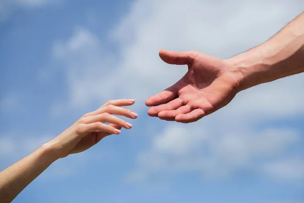 Férfiak és nők keze nyújtózkodik egymás felé, támogatva őket. Segítő kezet nyújtok. Férfiak és nők kezei a kék ég hátterében. Segítő kezet nyújtok. Szolidaritás, együttérzés és jótékonyság, mentés — Stock Fotó