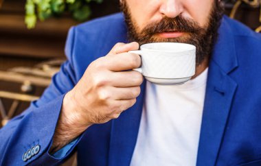 Sakallı adam sabahları kafede kahve ya da kahve tutar. Bir fincan kahve. Cappuccino ve siyah espresso fincanı. Kahve içeceğim. Sakallı adam, elleri sıcak kahve fincanı tutuyor. Kahve zamanı.