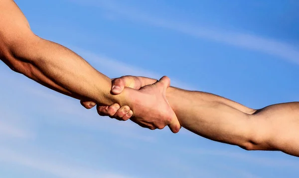 Manos en el fondo azul del cielo. Ayudar al concepto de la mano y el día internacional de la paz, el apoyo. Dos manos, brazo de un amigo, trabajo en equipo —  Fotos de Stock