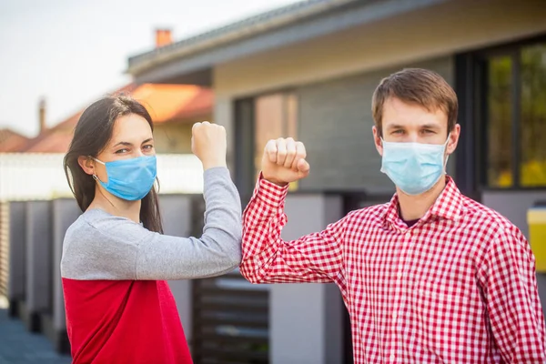 Elbow bump. Coronavirus, illness, quarantine, medical mask, COVID19. Couple greeting with elbows. Elbows bump. Friends in protective medical mask on his face greet their elbows in quarantine