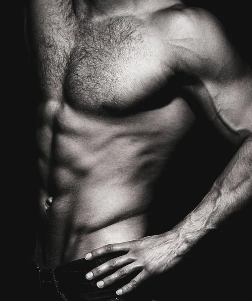Gövdesi olan kaslı seksi bir adam. Siyah arka planda kaslı bir spor mankeni. Çıplak ve güçlü kasları olan şehvetli bir adam. Gövde kasları yakın. Gövde konsepti. Siyah ve beyaz