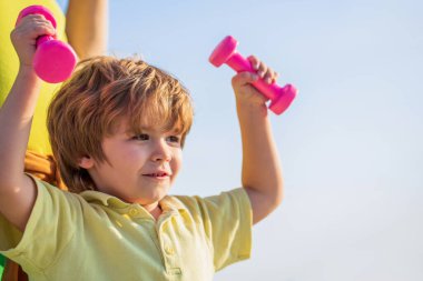 Neşeli çocuk halterlerle egzersiz yapıyor. Fitness çocuğu. Çocuk dambıllarla egzersiz yapıyor. Küçük çocuklar için spor. Dambılı sportif çocuk. Spor. Fitness, sağlık ve enerji. Sağlıklı yaşam tarzı