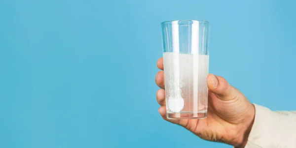 Primer plano del hombre sosteniendo una píldora. Un vaso de agua. Vidrio con tableta efervescente en agua con burbujas —  Fotos de Stock