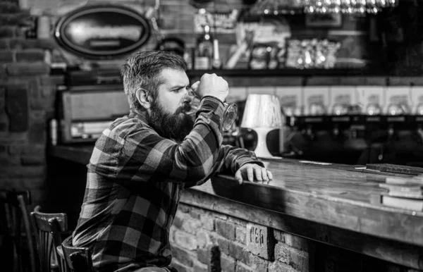 Il boit des bières au comptoir du bar. Un homme avec de la bière. Le hipster barbu tient un verre de bière. Un pub de bière. Un chic type au café pub. Noir et blanc — Photo