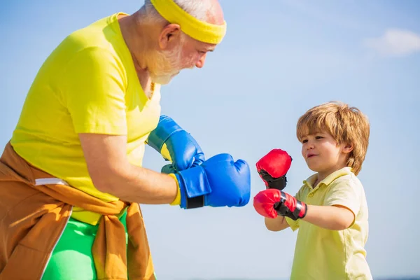 Little boy doing boxing exercise with grandfather. Father is training his son boxing. Little boy sportsman at boxing training with coach — Stock Photo, Image