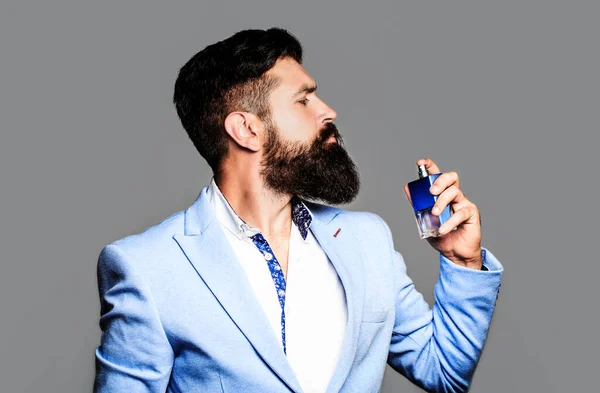 Perfume or cologne bottle, perfumery, cosmetics, scent cologne bottle, male holding cologne. Masculine perfume, bearded man in a suit. Male holding up bottle of perfume. Man perfume, fragrance