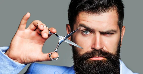 Male in barbershop, haircut, shaving. Bearded man isolated on gray background. Mans haircut in barber shop. Barber scissors, barber shop. Brutal man, moustache — Stock Photo, Image