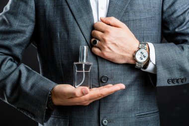 Parfüm, parfüm şişesi, parfüm, kozmetik, parfüm şişesi, erkek parfümü. Erkek parfüm şişesi tutuyor. İş elbisesi içinde kol saatiyle teslim ol.