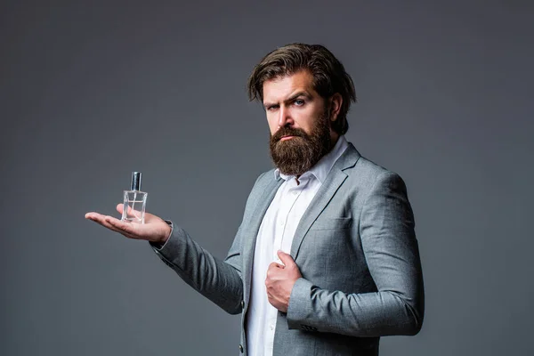 Man perfume, fragrance. Perfume or cologne bottle, perfumery, cosmetics, scent cologne bottle, male holding cologne. Masculine perfumery, bearded man in a suit. Male holding up bottle of perfume — Stock Photo, Image
