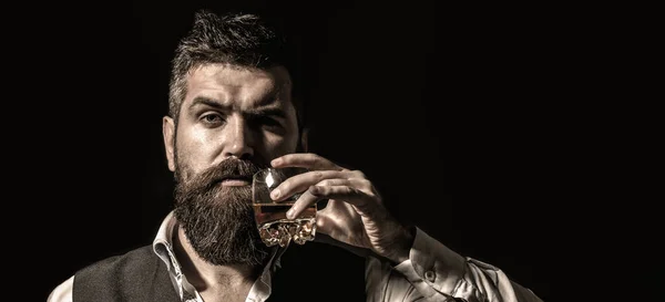 Rik man med glaswhisky. Attraktiv man med whisky. Snygg snygg hane i kostym dricka från glas konjak, konjak. Porträtt av ett vackert skägg i elegant smoking, dricka konjak — Stockfoto